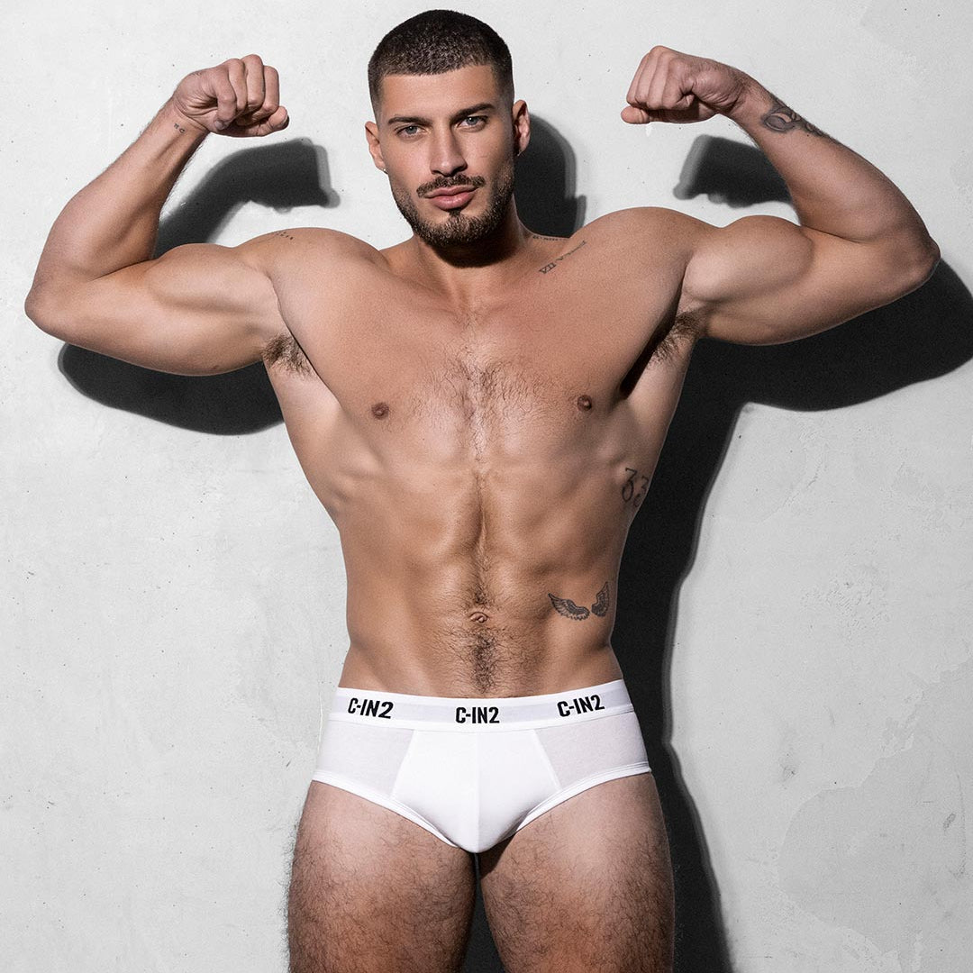 Muscular man wearing white underwear with a gray background