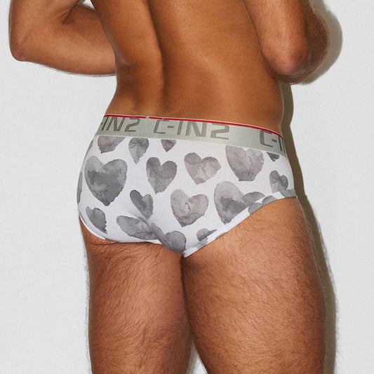 Rear view of a man wearing white briefs with a gray heart pattern and a gray waistband featuring the brand name C-IN2.