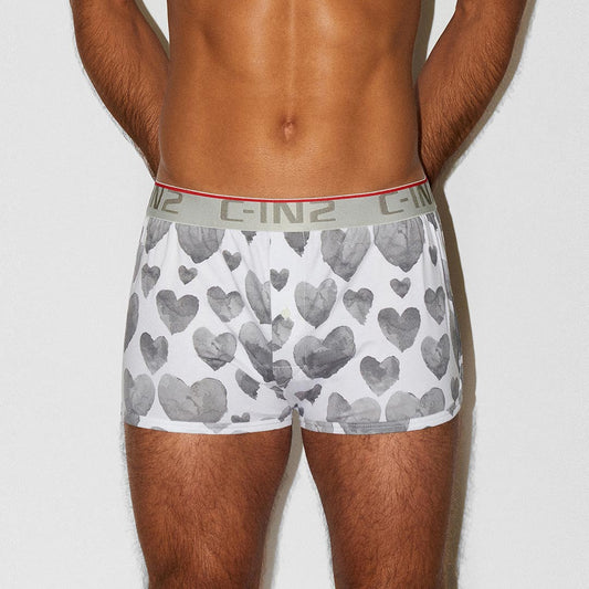 A man wearing white boxer briefs with a gray heart pattern and a gray waistband with 'C-IN2' branding, shown from the waist down against a light gray background.