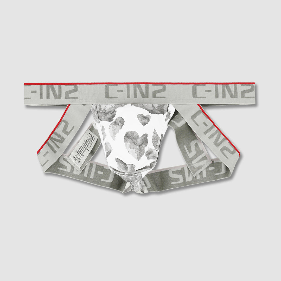 A pair of low-rise briefs by GIN2, featuring a white and gray heart-print center panel, a wide gray elastic waistband with repeating 'C-IN2' text and a thin red stripe, and red piping along the leg openings.