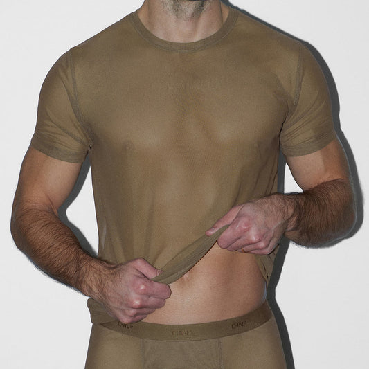Man wearing a sheer beige t-shirt against a white background
