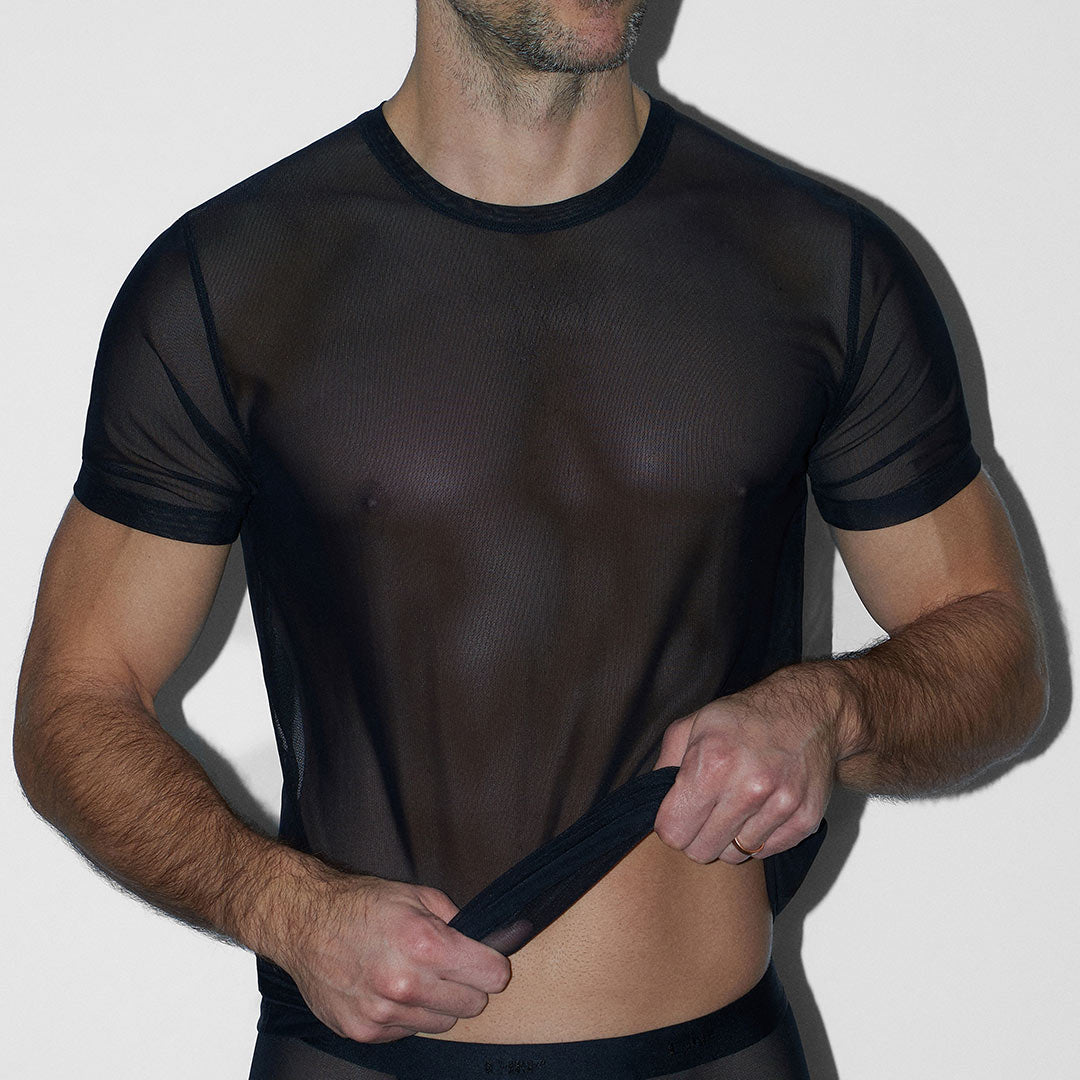 Man wearing a sheer black outfit against a white background