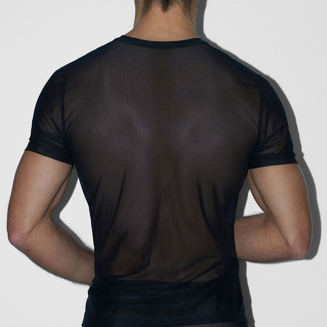Person wearing a sheer black mesh shirt against a white background