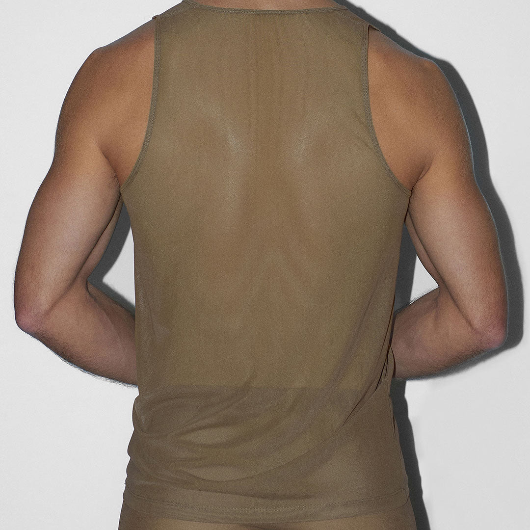 Person wearing a sheer brown tank top and shorts against a white background