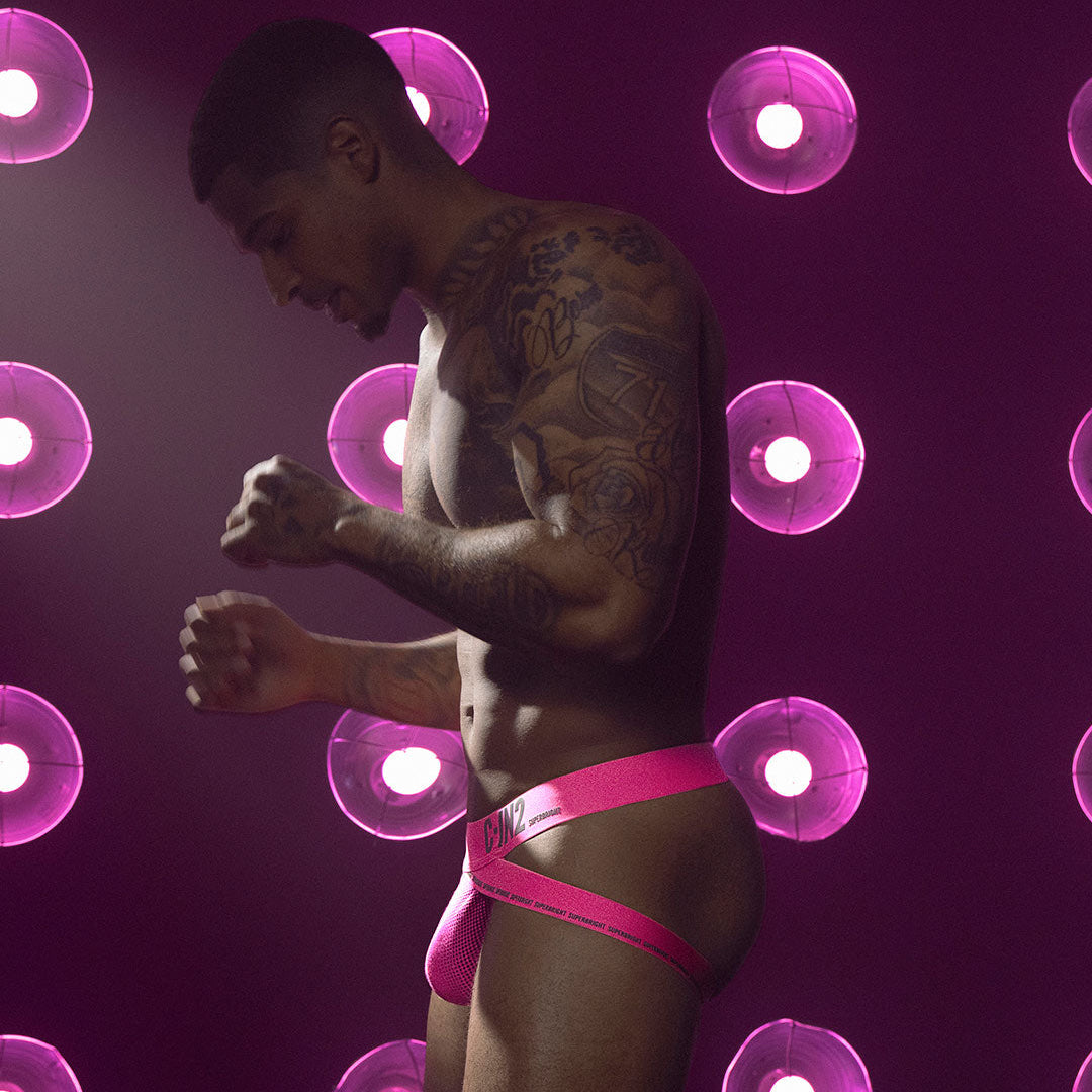 Man wearing pink jock against a purple background with glowing circular lights