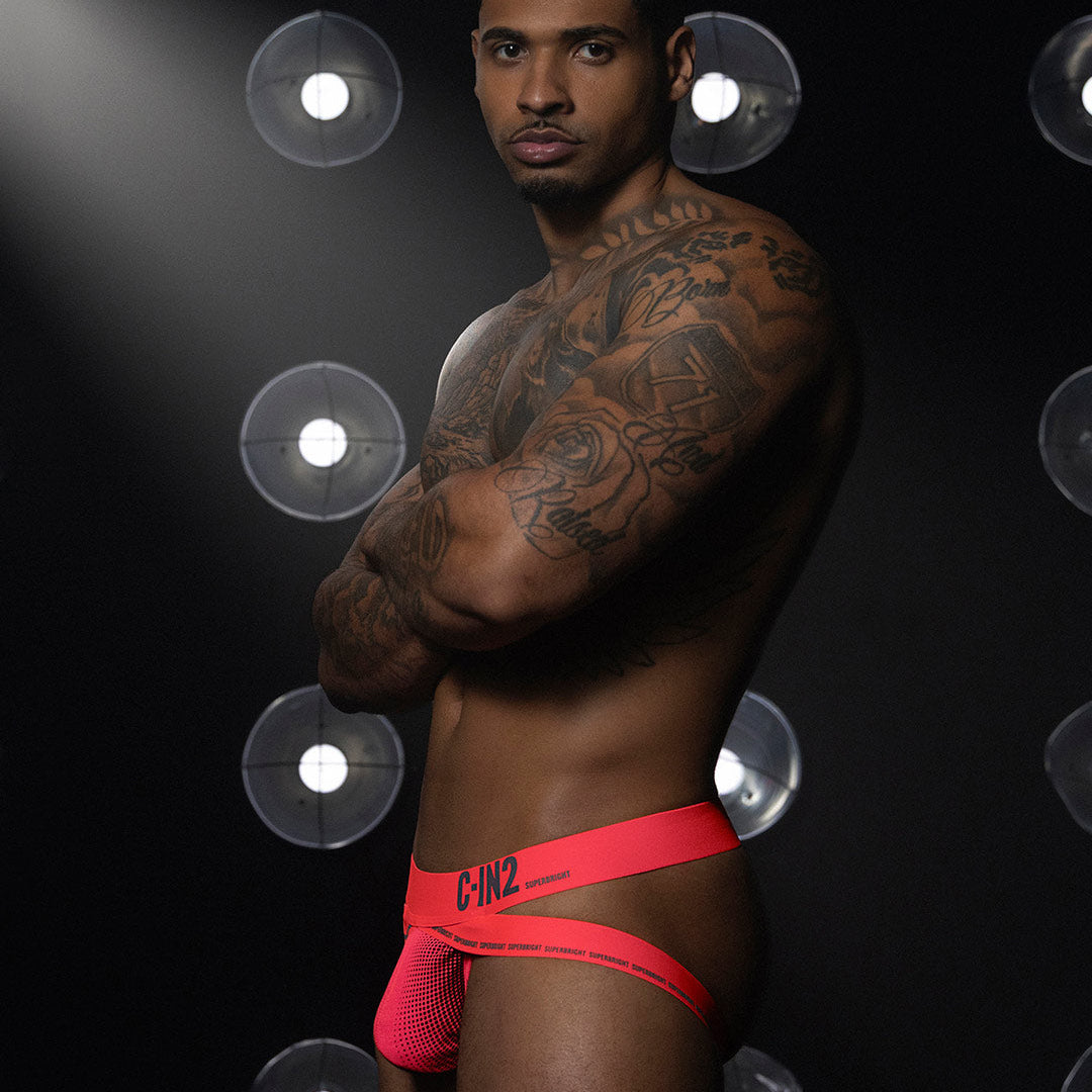 Man wearing a red underwear with visible C-IN2 branding against a dark background with spotlight effect
