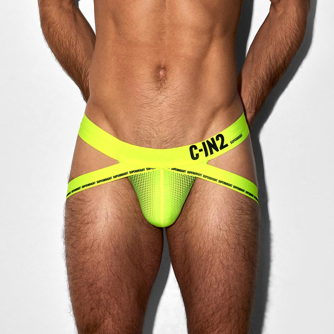 A close-up of a male model wearing bright neon yellow-green jock-style underwear with black printed branding text 'C-IN2' on the front waistband, against a plain light gray studio background.