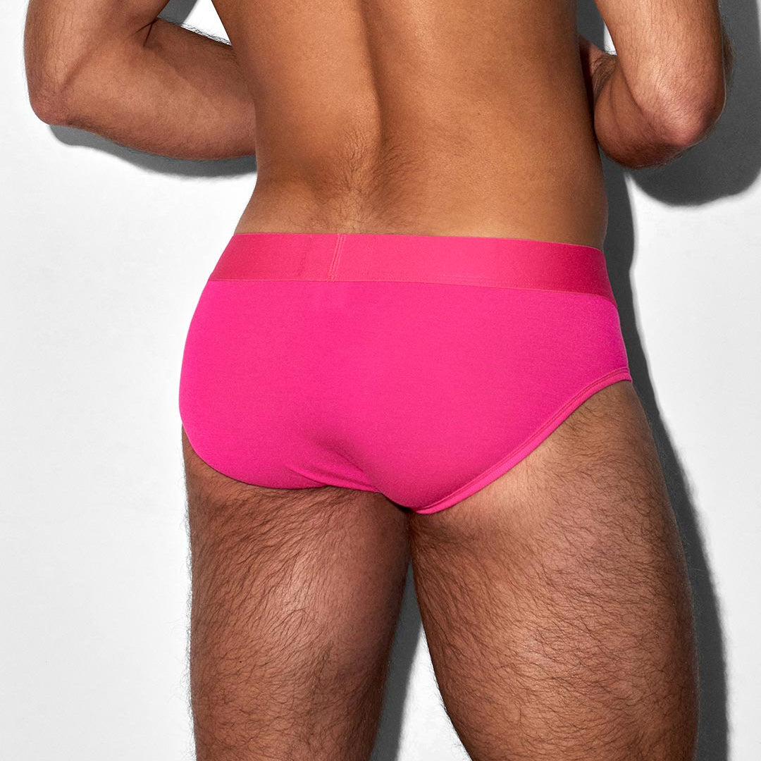 Person wearing bright pink underwear on a light gray background