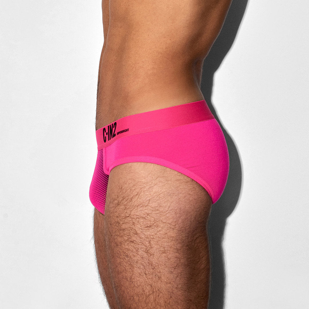 Person wearing bright pink underwear with a brand logo on a white background