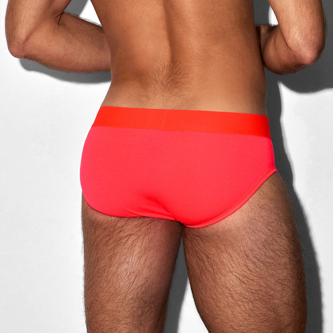Person wearing bright red swim briefs on a plain background