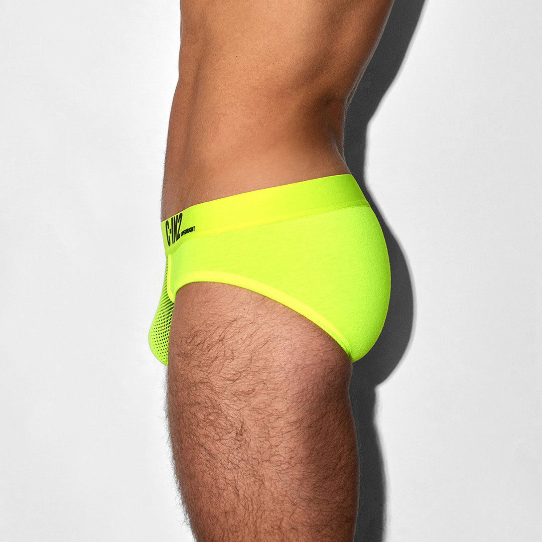 Neon green swim brief worn by a person on a white background