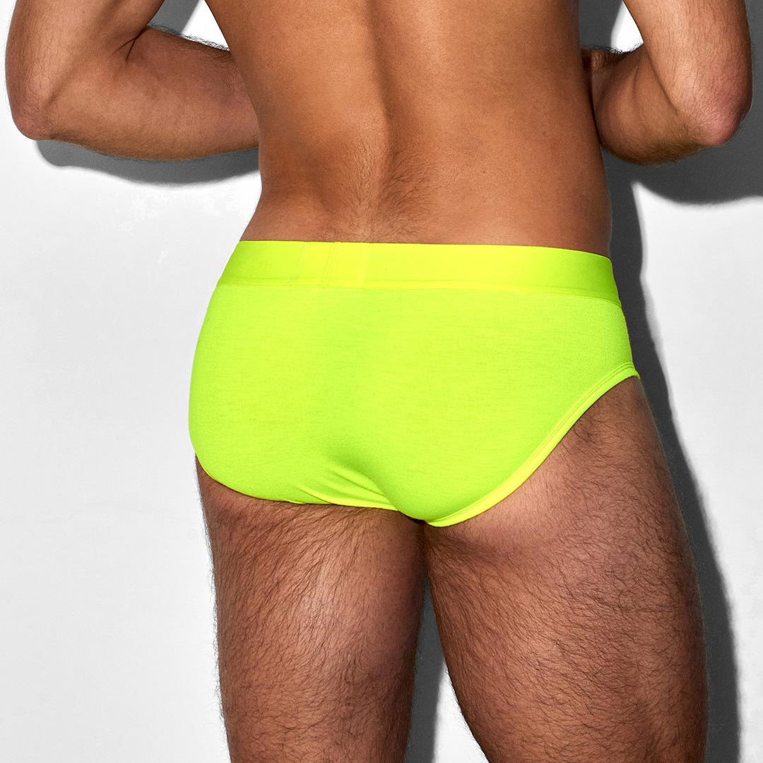 Person wearing bright green swim briefs on a plain background