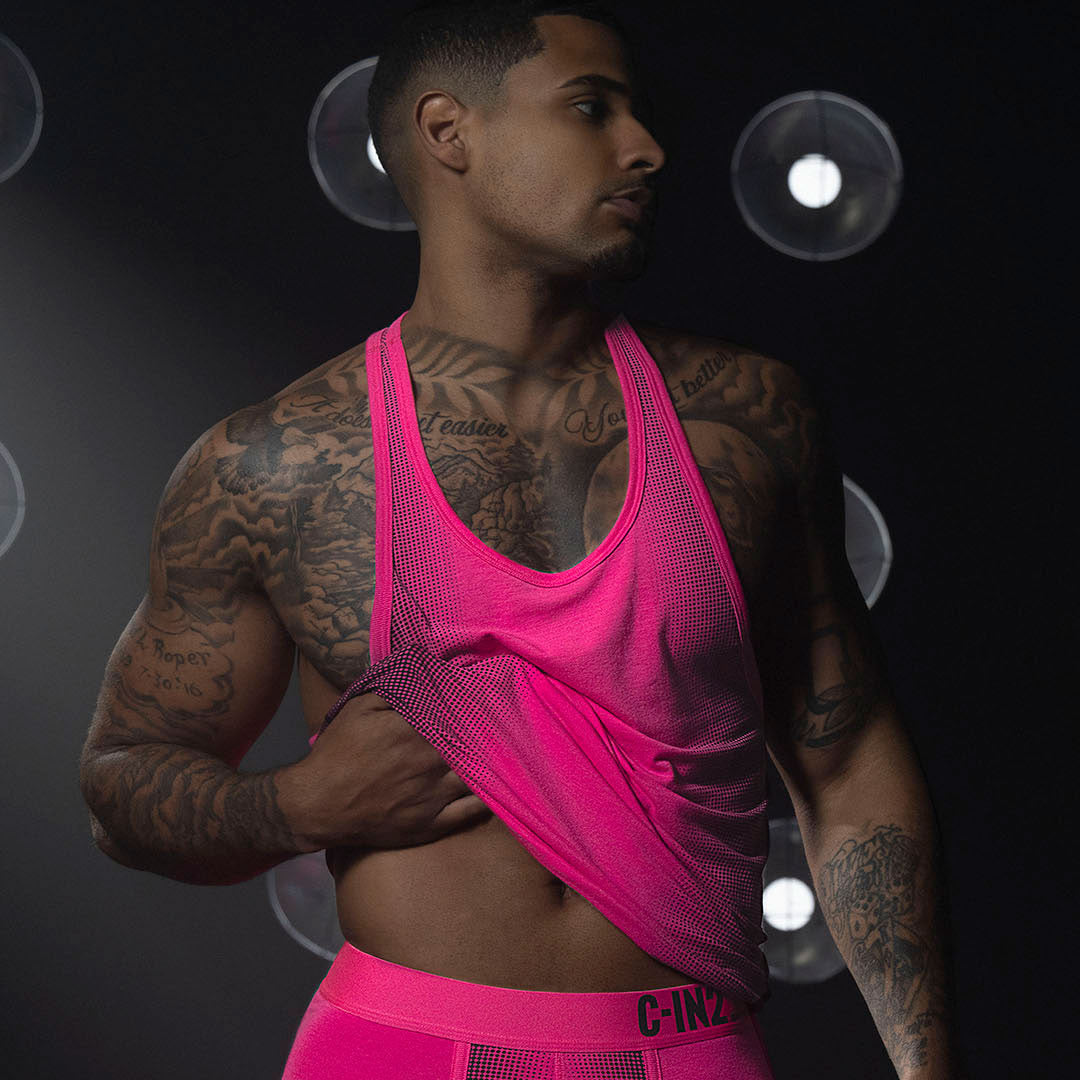 Man wearing bright pink athletic wear with a dark background