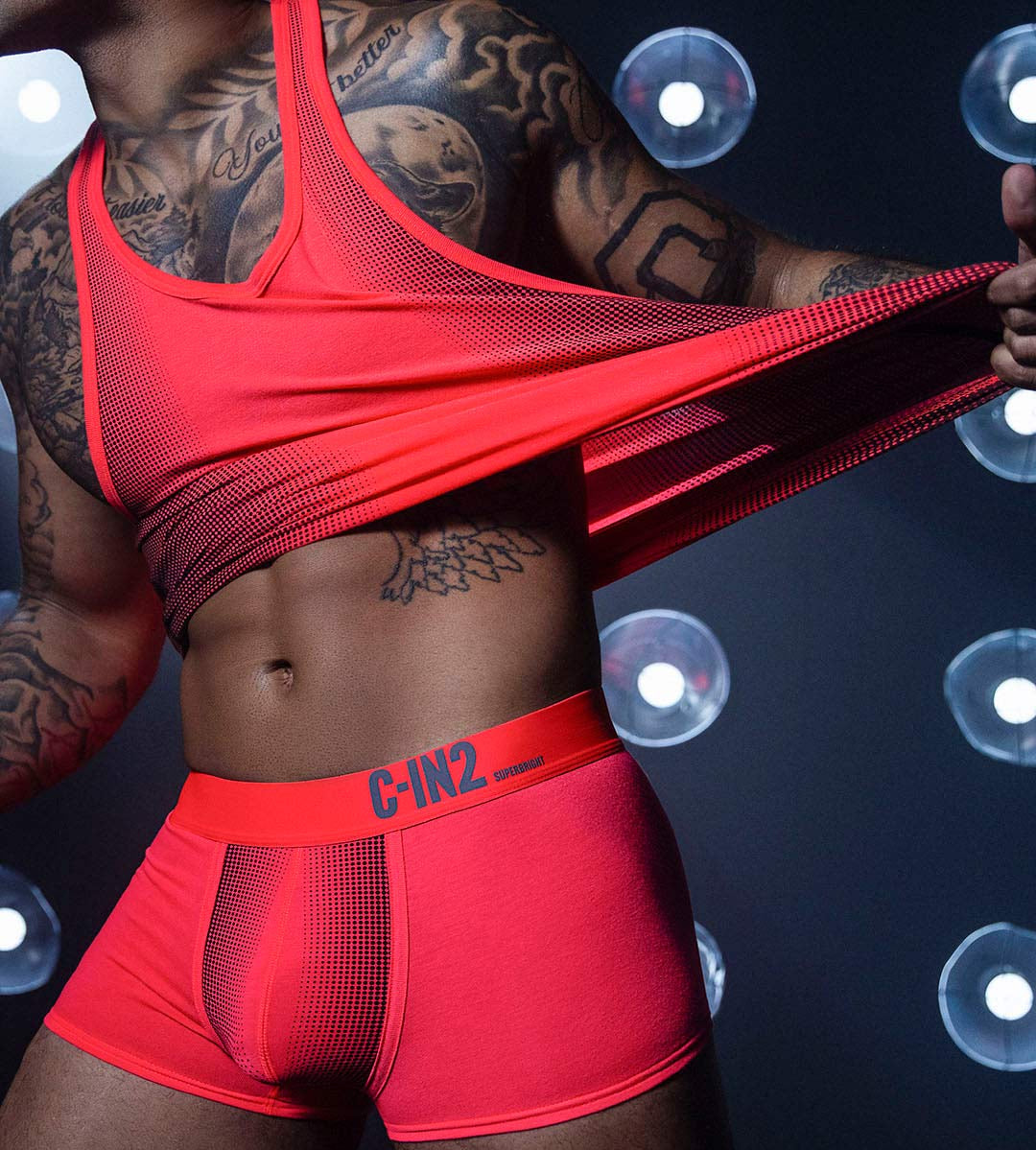 Person wearing red underwear with a visible brand logo against a dark background with light effects.