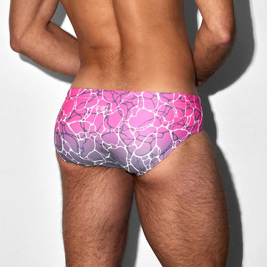 Person wearing a pink and purple patterned swim brief with C-IN2 branding on a white background