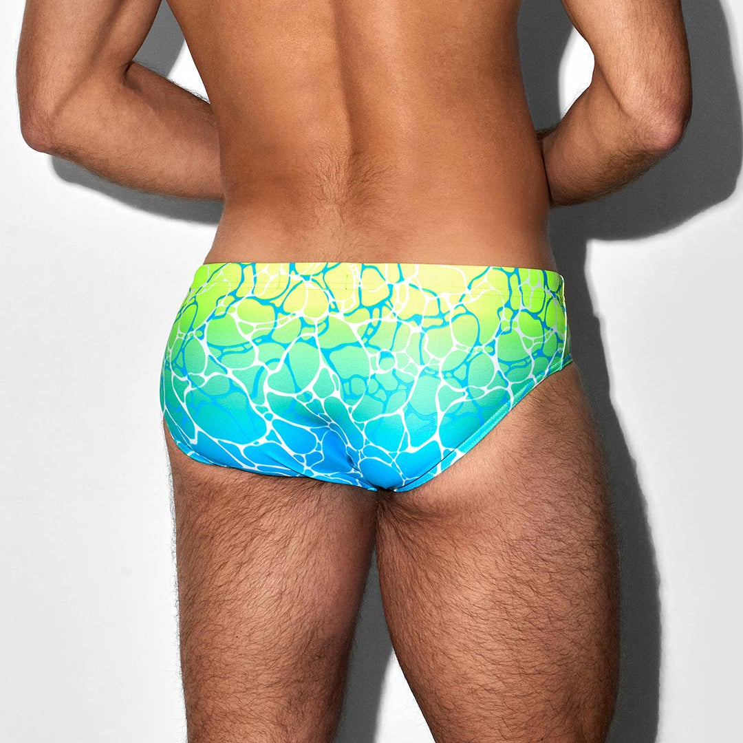 Man wearing a colorful swim suit on a plain background
