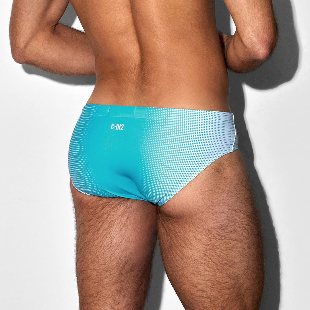 Man wearing turquoise swim briefs with C-IN2 logo against a white background
