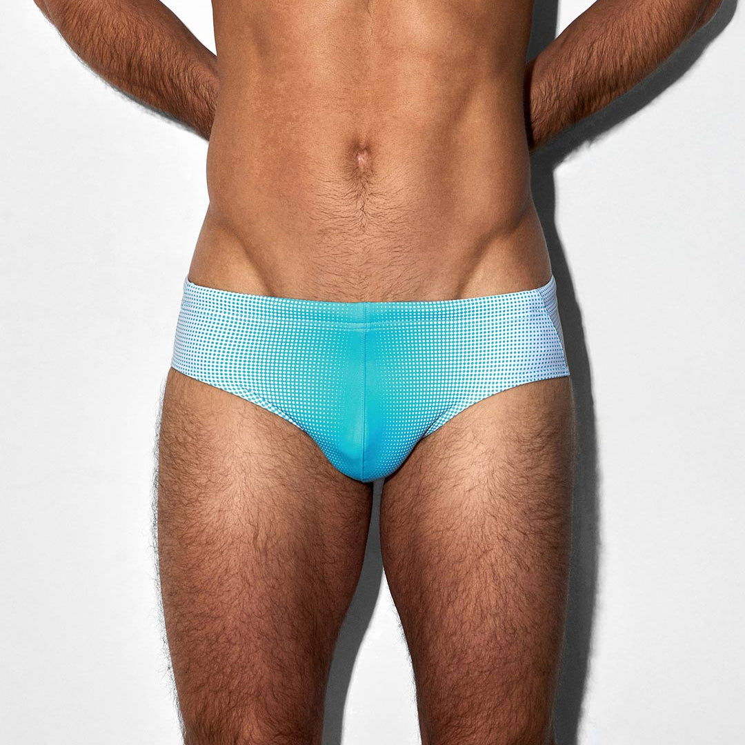 Man wearing light blue swim briefs on a white background