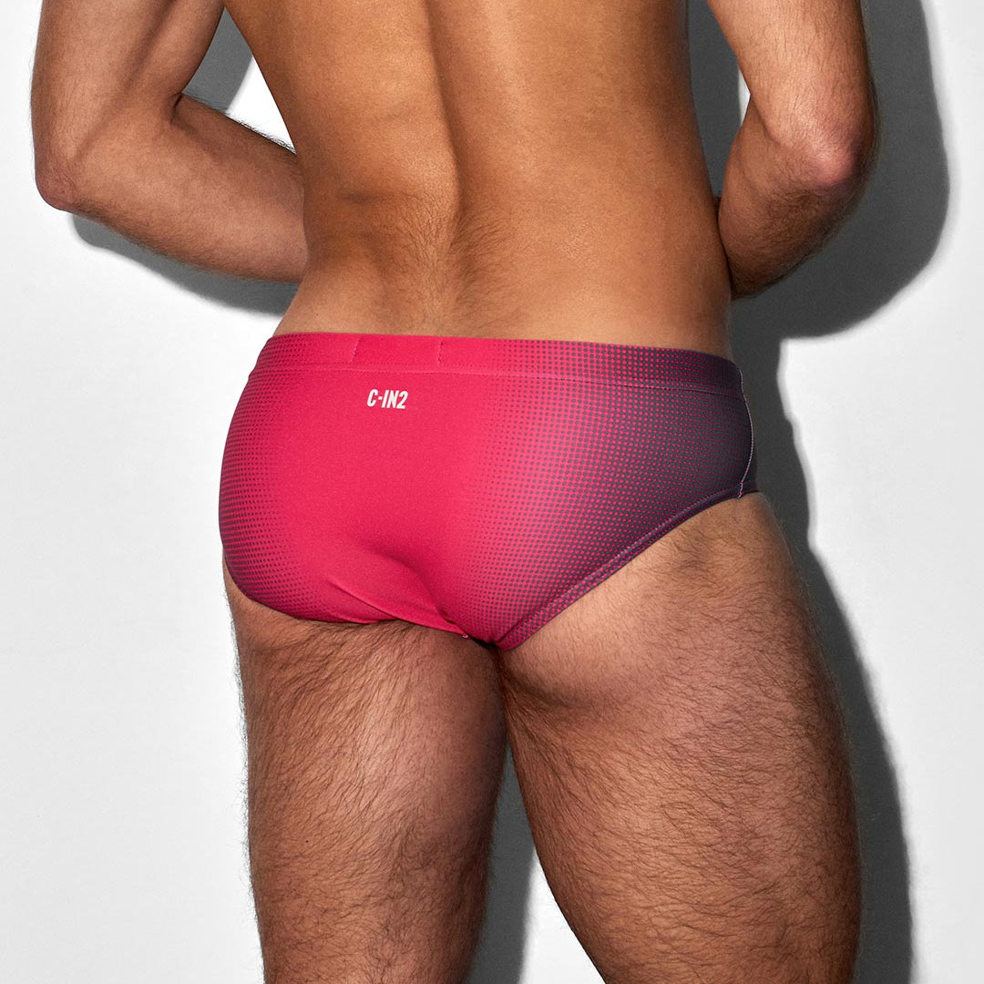 Person wearing a red men's bikini swim brief with a C-IN2 brand logo on a white background