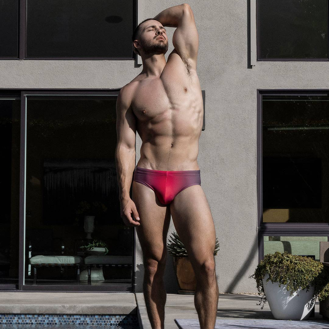 Man in red swim brief standing by a poolside