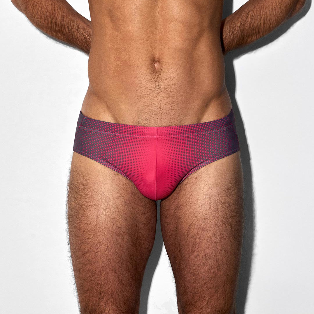 Man wearing a red patterned swim brief on a white background
