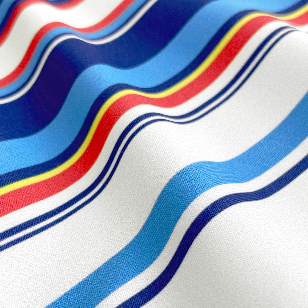 Close-up of fabric with wavy red, blue, and yellow stripes on a white background