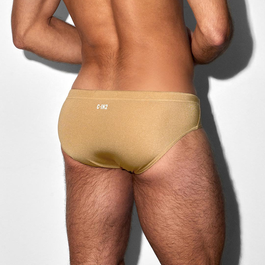 Man wearing a champaign-nude colored swim brief with 'C-IN2' branding on a white background