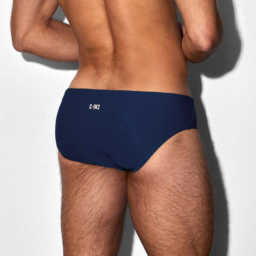 Man wearing navy blue swim briefs with a 'C-IN2' brand logo on a white background