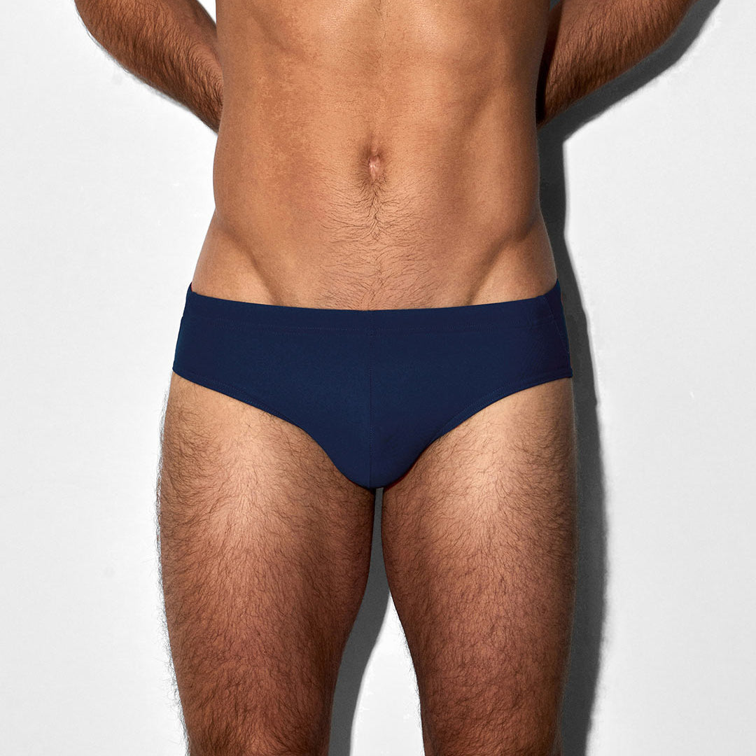 Man wearing a navy blue swim brief on a white background