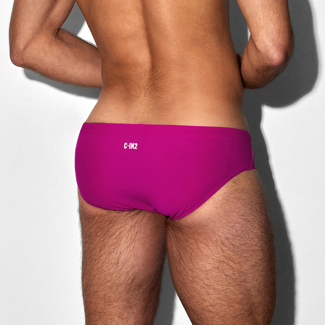 Person wearing a bright pink swim brief with 'C-IN2' branding on a white background