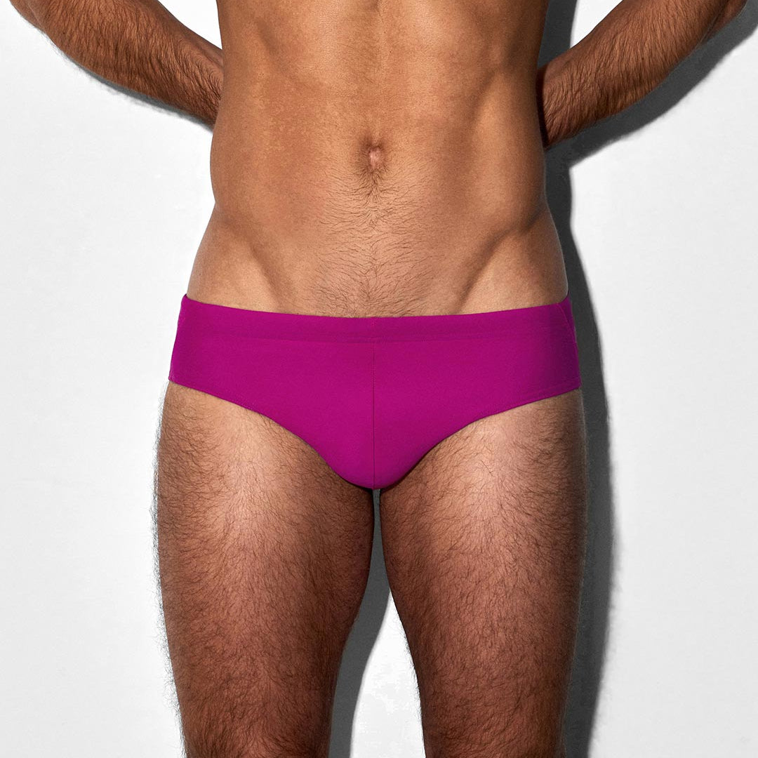 Man wearing bright pink swim brief on a white background