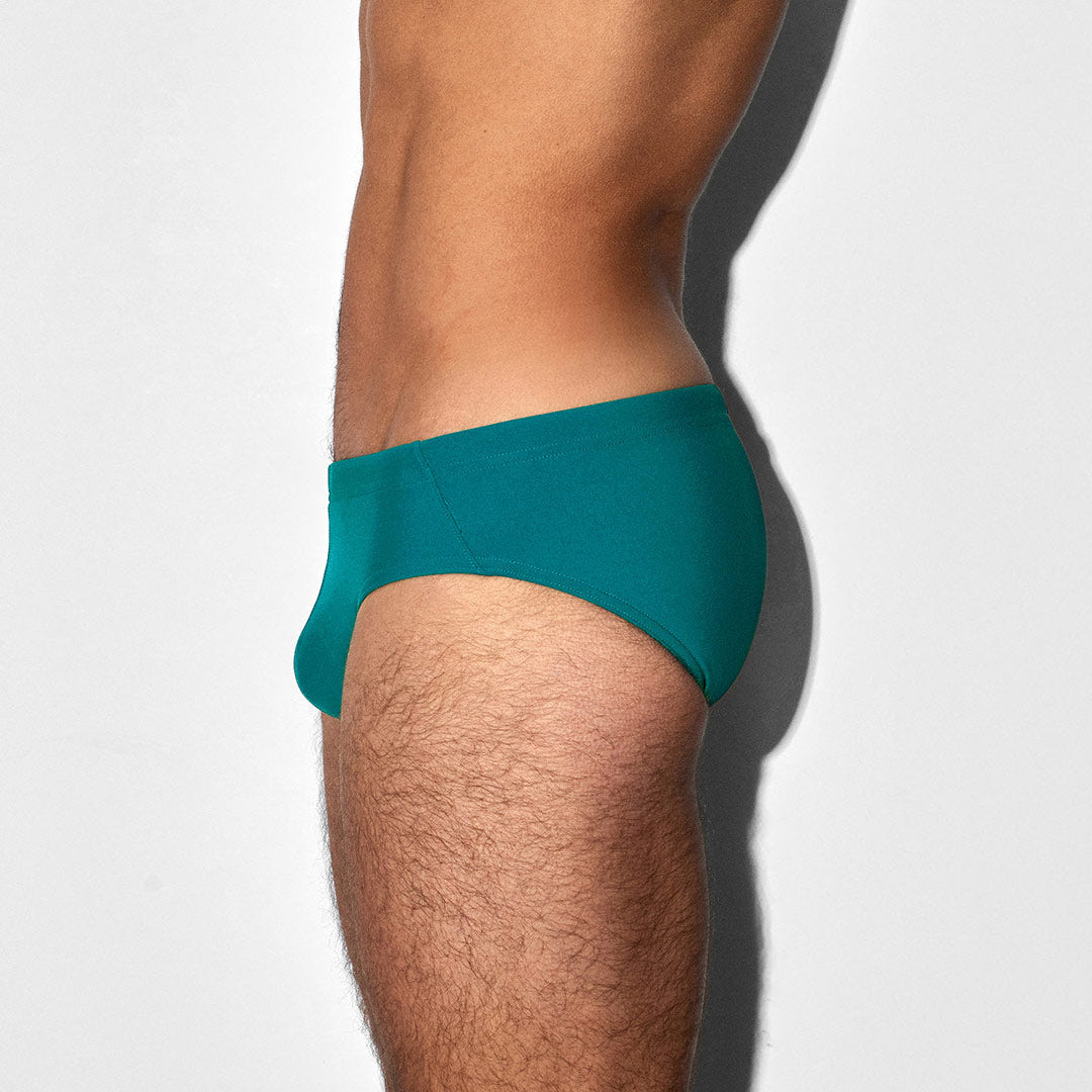 Teal swim brief worn by a person on a white background