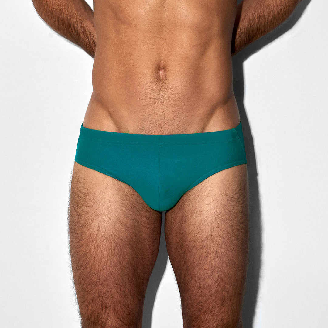 Man wearing teal swim brief on a white background