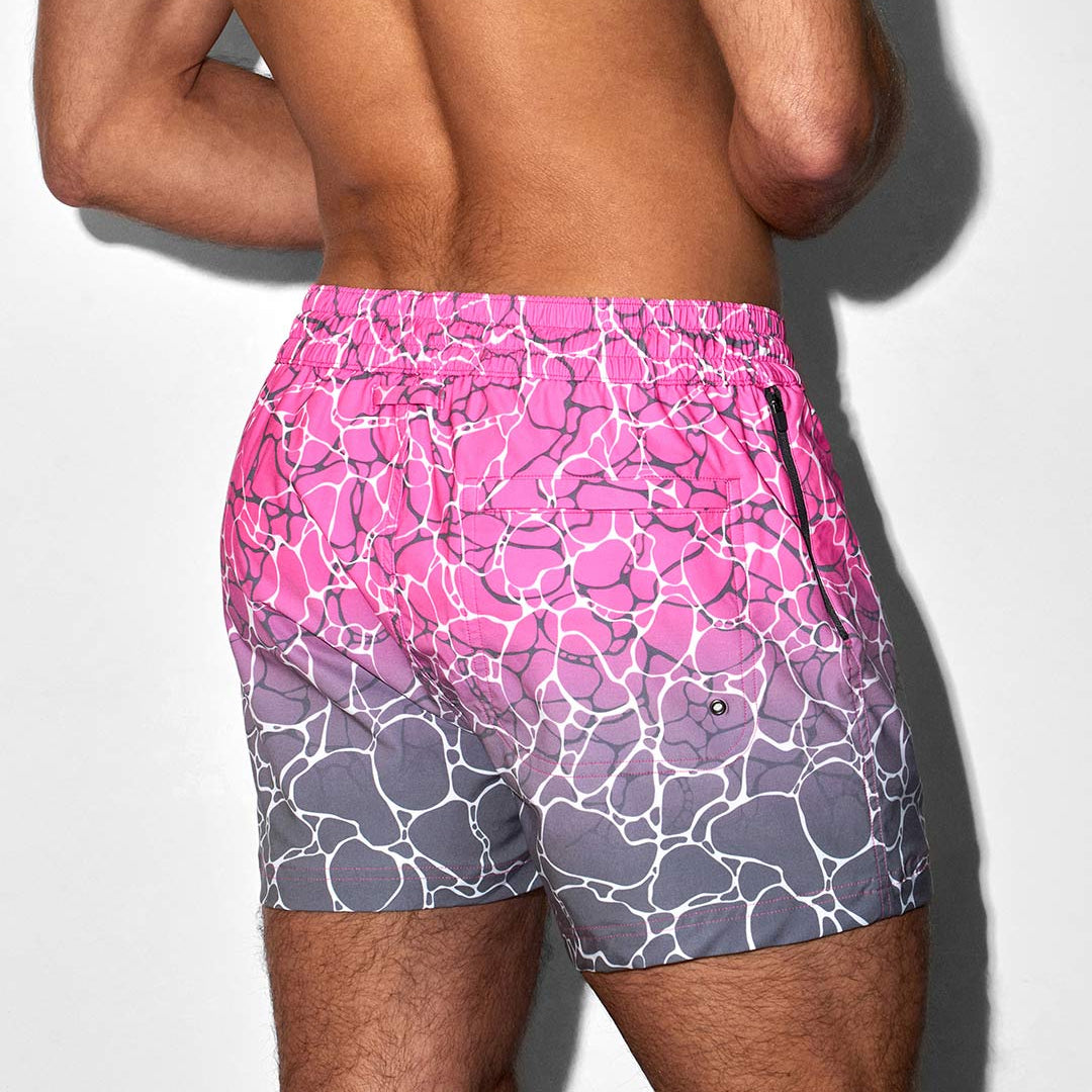 Person wearing pink and gray patterned swim shorts on a white background
