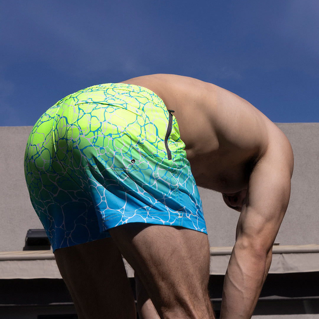Person wearing a colorful swim cap with a blue and green pattern against a clear sky.