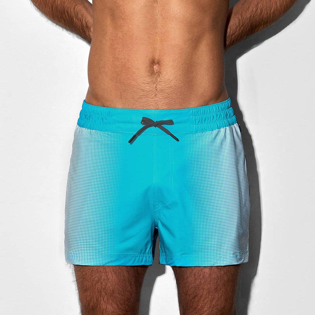 Man wearing turquoise swim shorts on a white background
