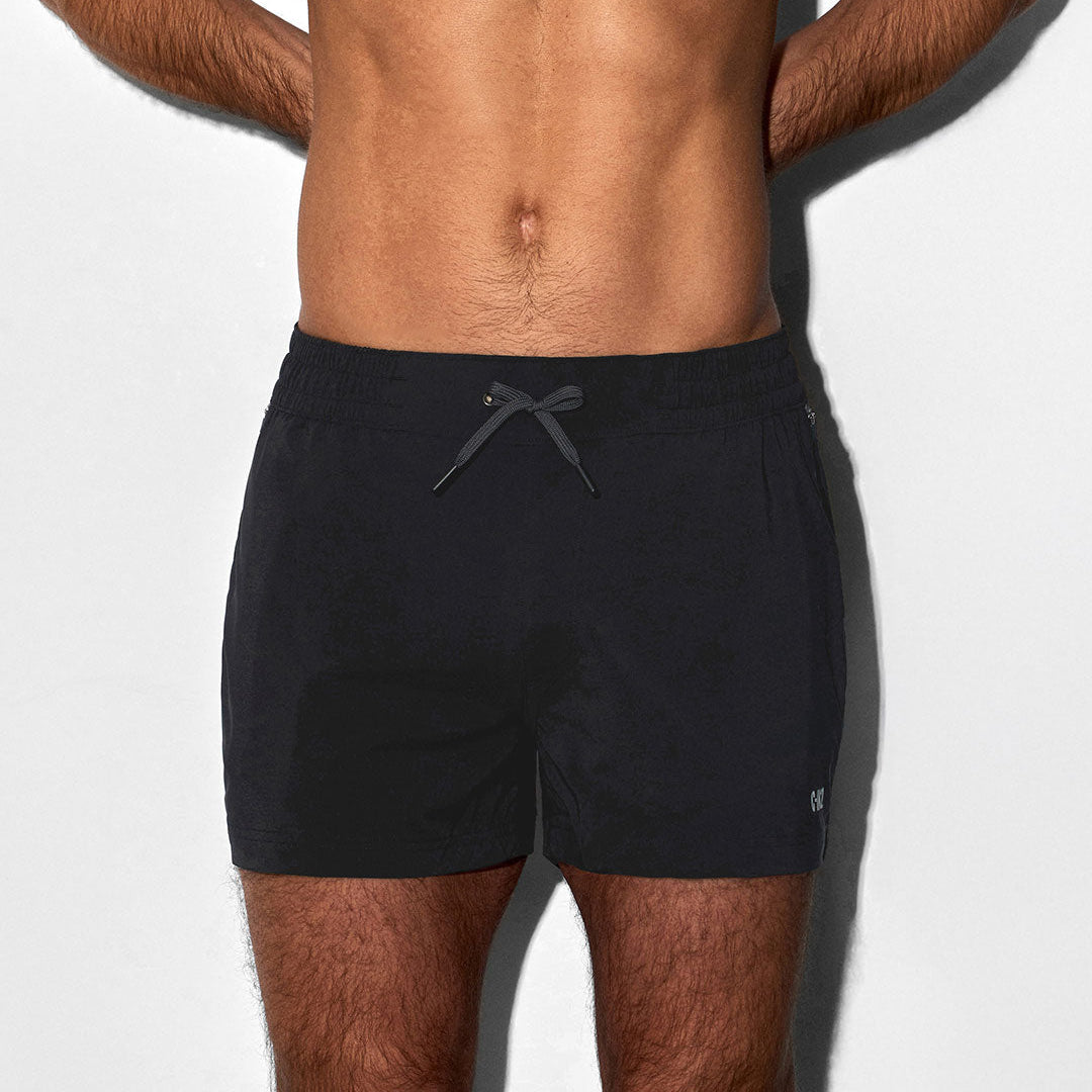 Man wearing black swim shorts with 'C-IN2' branding on a white background