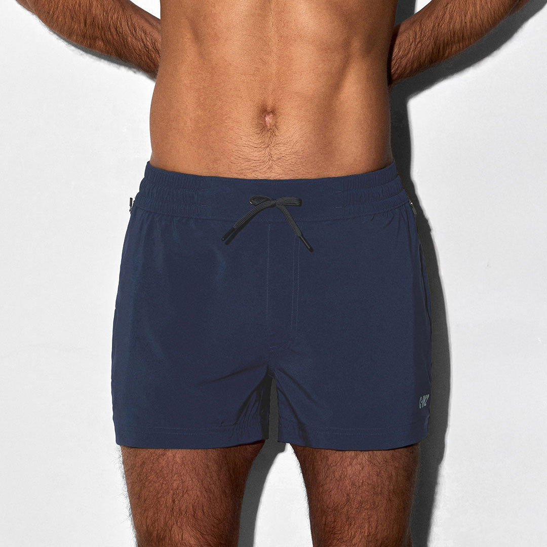 Man wearing navy blue C-IN2 branded swim shorts on a light gray background
