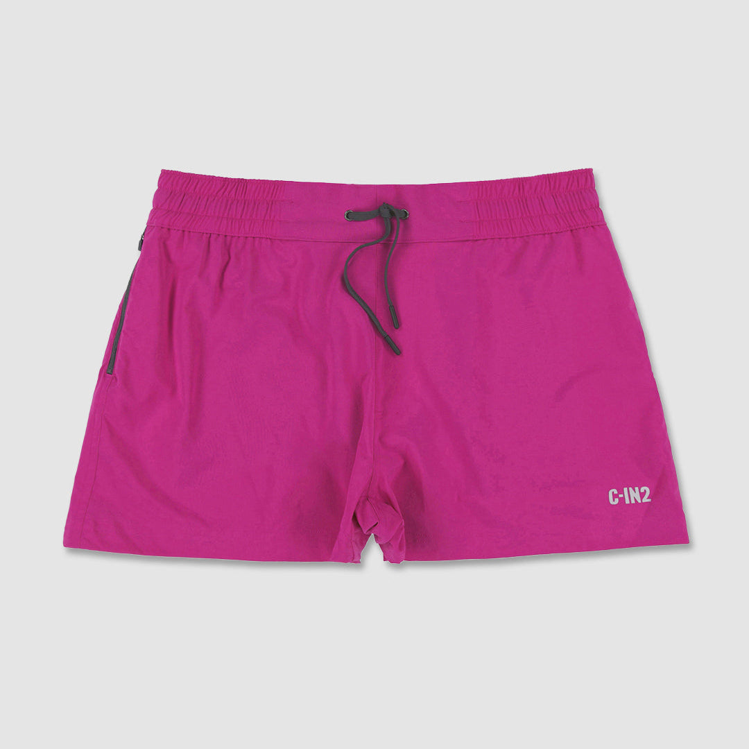 Bright pink swim shorts with a dark gray drawstring and a small white C-IN2 logo on the lower left leg, displayed flat against a light gray background.
