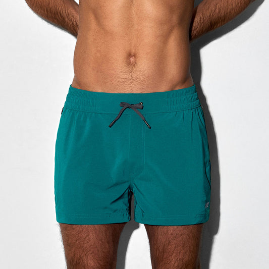Man wearing teal swim shorts on a white background