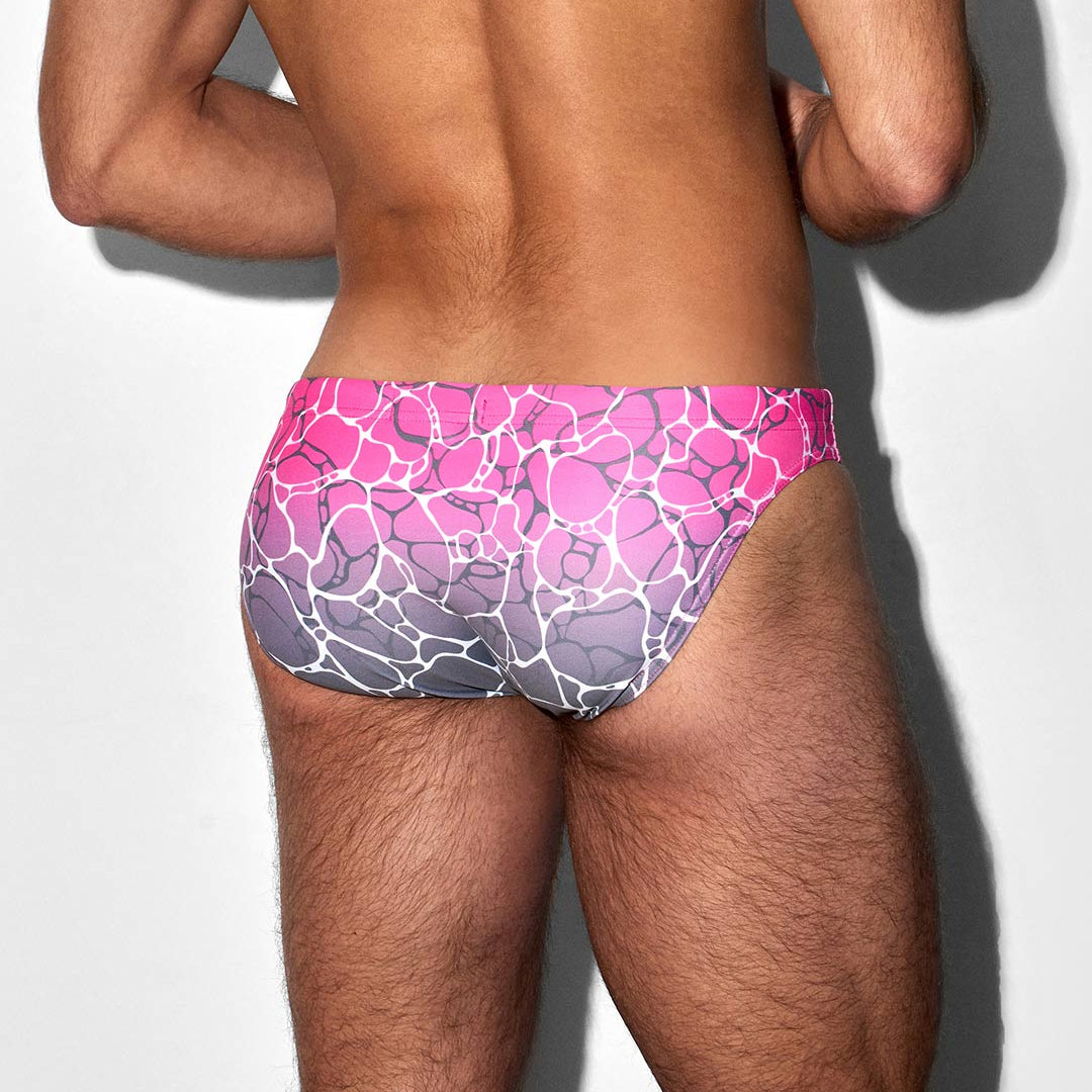 Person wearing a colorful pink pattern swim brief on a plain background