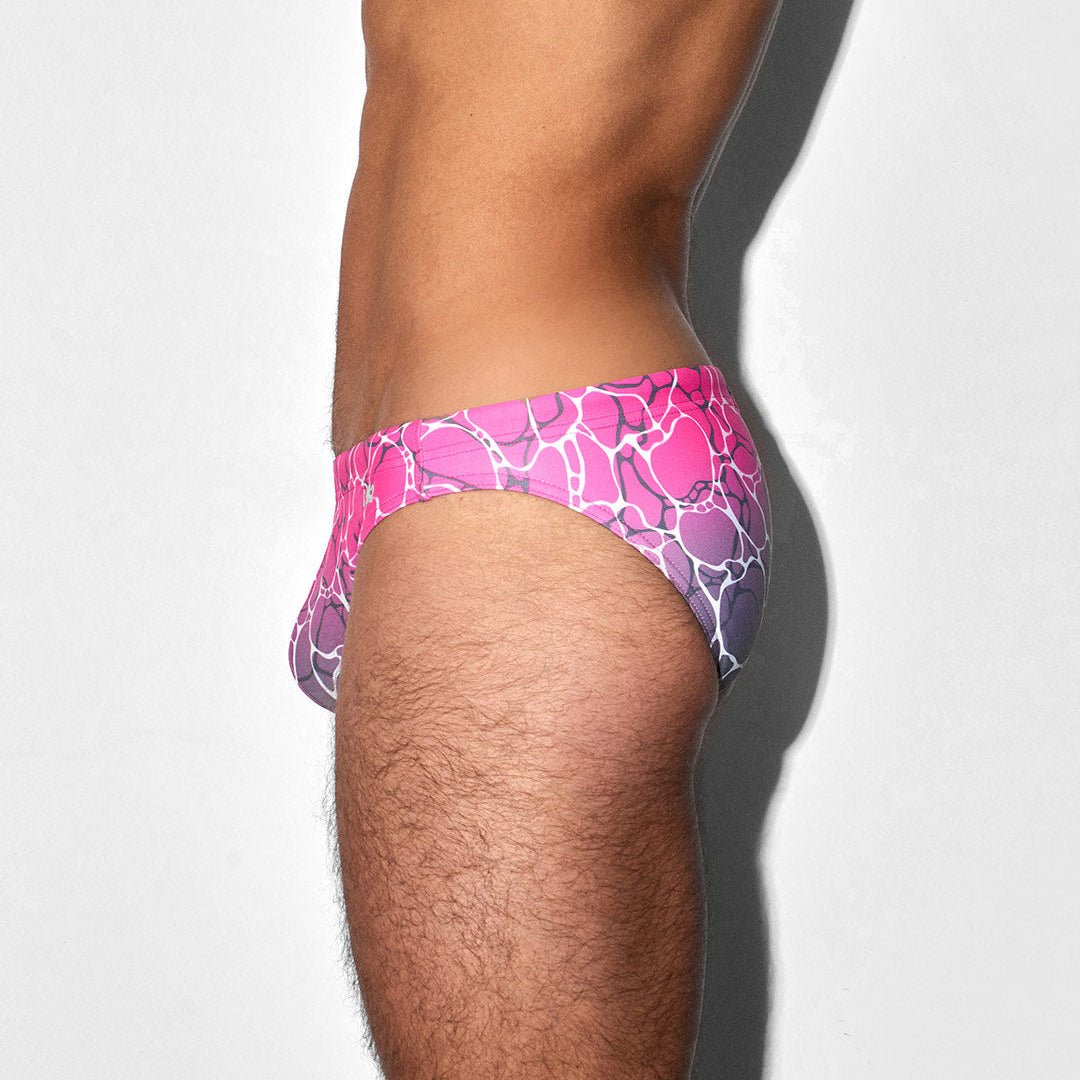 Pink and purple patterned swim brief on a person against a white background