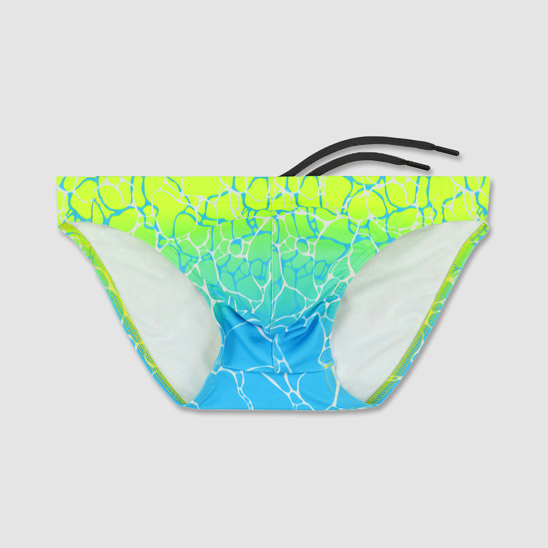 A pair of men's bikini bottoms featuring a vibrant water ripple pattern with a gradient transition from neon yellow-green at the top to bright blue at the bottom, with white interior lining and black side ties, shown against a solid light gray background.