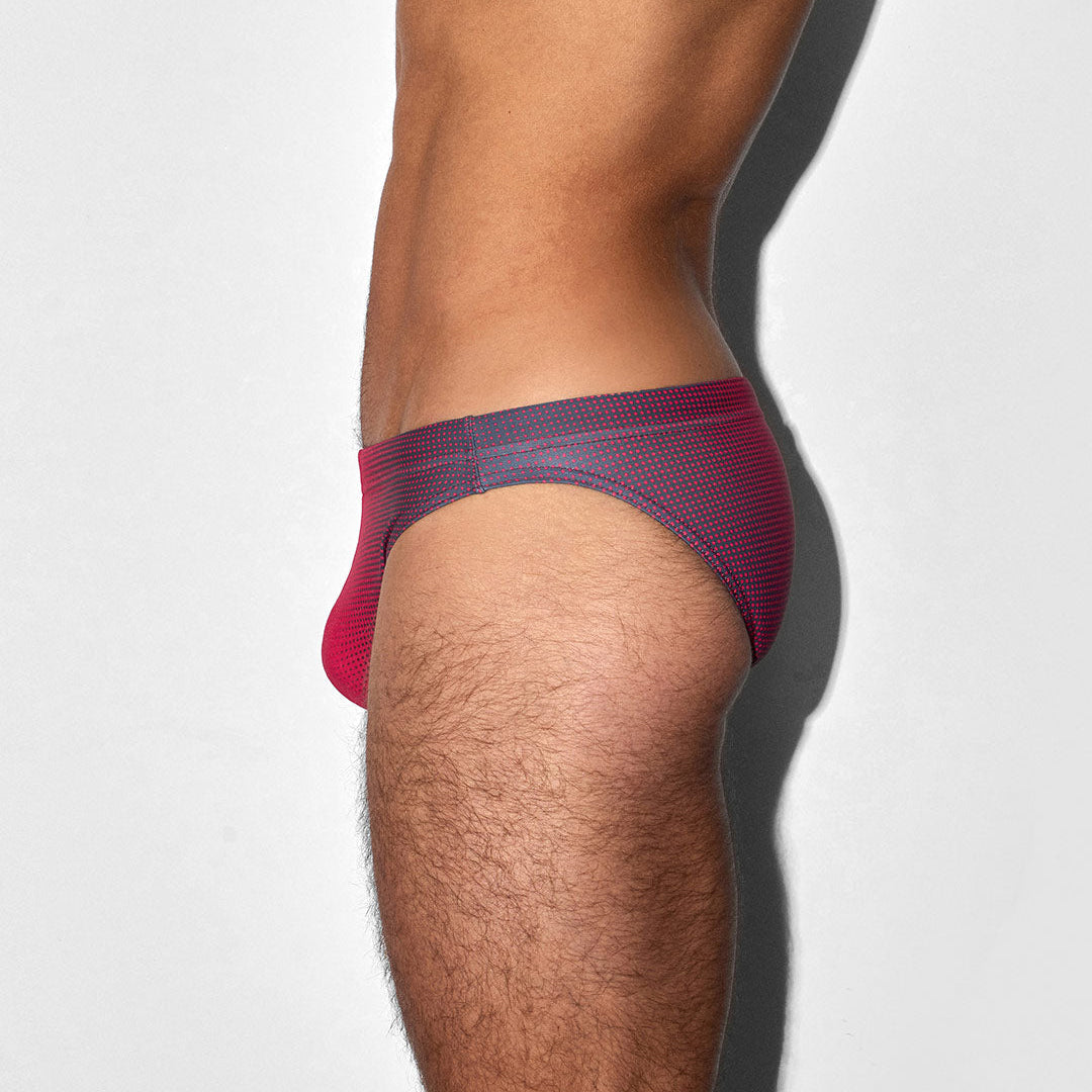 Red men's bikini swim brief worn by a person on a white background