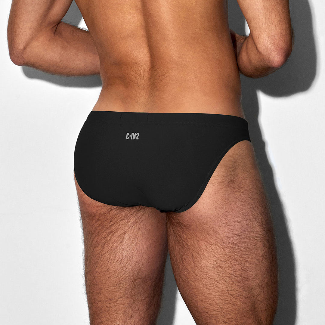 Back side of a man wearing a black swim brief with a 'C-IN2' brand logo on a white background