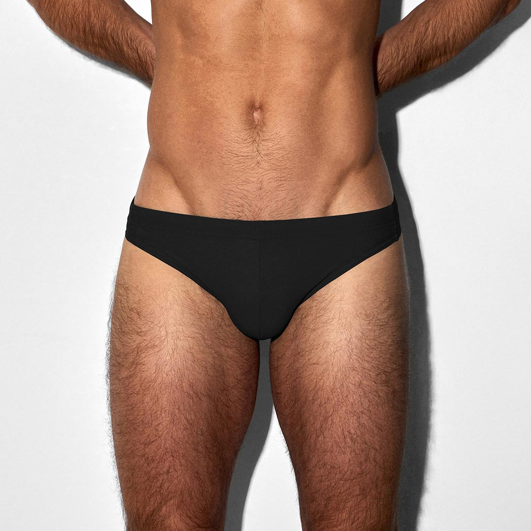 Man wearing a black swim brief against a white background