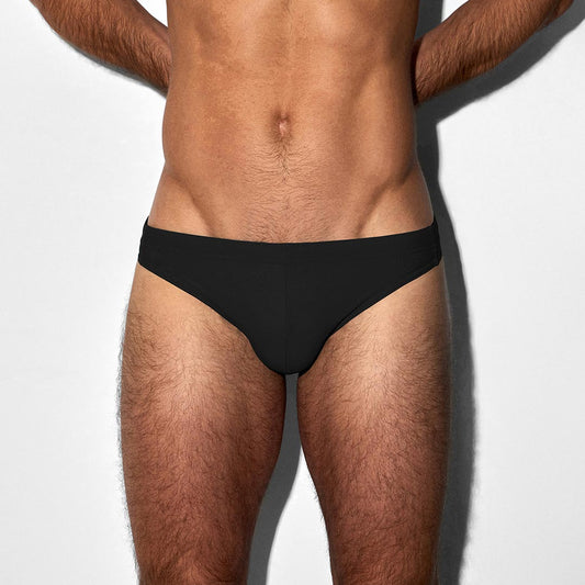 Man wearing a black swim brief against a white background