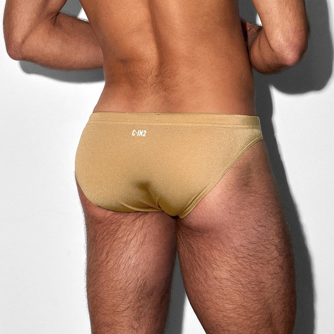 Man wearing a Champaign colored swim brief with a 'C-IN2' brand logo on a light gray background