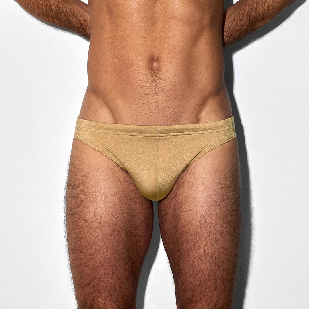 Man wearing champaign colored swim brief against a white background