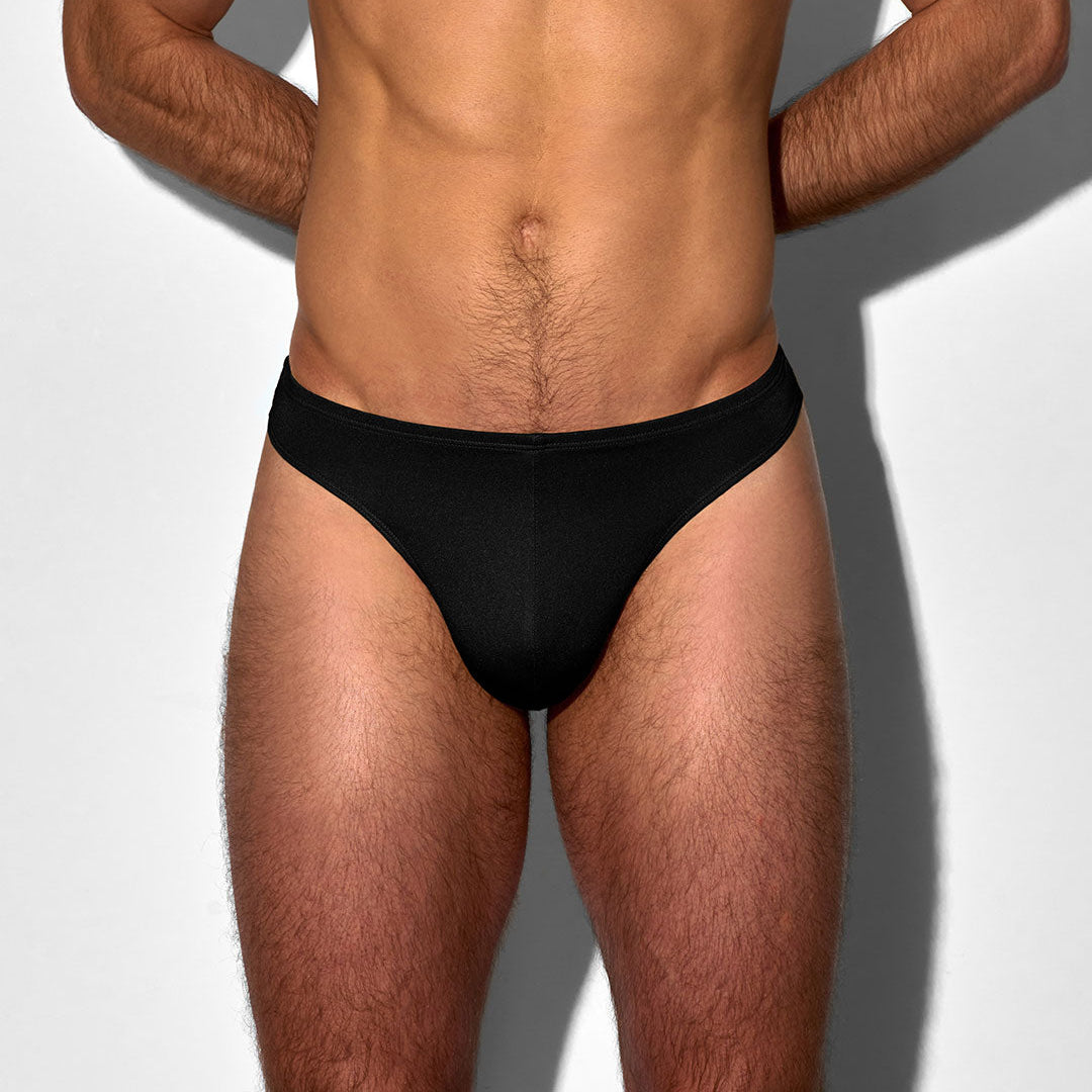 Man wearing a black men's swim thong on a white background